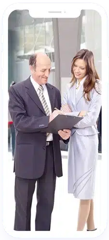 A man and woman in business attire review a clipboard together, both framed inside the outline of a smartphone graphic.